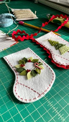 two christmas stockings are sitting on a table next to some scissors and sewing threads