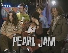 a group of people sitting next to each other in front of a sign that says pearl jam