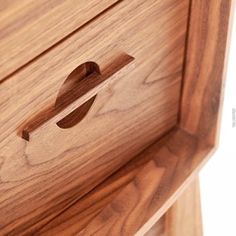 a close up of a wooden drawer with a hole in the middle and a handle on it