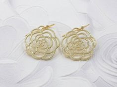 These are pair of beautiful camellia rose earrings. They are made with golden plated over brass flower shaped filigree pendants. The flower is available in two different golden color. The gold color is in a deep gold; and light gold color is in a light gold tone. The earrings measure about 31mm (1.25 inches) from the top of the ear wires to the bottom of the flower. They are perfect for many occasions, gift giving or as a little treat for yourself. Your earrings will presented in a jewelry gift Gold Rose Design Earrings For Wedding, Gold Rose Design Earrings For Anniversary, Formal Gold Earrings With Rose Design, Elegant Rose Earrings With Ear Wire, Elegant Rose Dangle Earrings, Formal Gold Flower Earrings With Rose Design, Elegant Rose Flower Earrings For Wedding, Gold Flower Earrings For Bridesmaid Gift, Gold Flower Earrings For Wedding