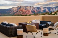 a patio with wicker furniture and fire pit in the foreground, surrounded by mountains