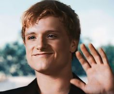 a close up of a person holding his hand near his ear and smiling at the camera