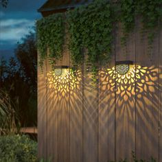 the lights are shining on the side of a wooden fence with ivy growing over it