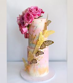 there is a pink cake with butterflies on it and flowers in the top tiers