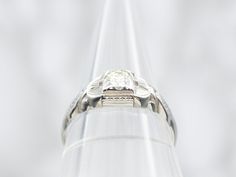 This small, elegant ring is simply gorgeous! Crafted of 18-karat white gold, this early Retro Era ring features an Illusion head at the center, which not only protects the diamond but which gives it a square shape with all of the sparkle of a round brilliant stone! Milgrain edging decorates the structural shoulders, giving this small ring presence and substance on the finger. Metal: 18K White Gold Gem: Diamond .20 Carat, K in Color, VS2 in Clarity Gem Measurements: 3.5 mm, Round Ring Size: 6.75Marks: "18K" Stamped on the inside band Formal Cushion Cut Diamond Ring With Single Diamond, White Gold Square Cut Diamond Ring With Single Diamond, Square Cut Single Diamond White Gold Ring, Diamond White Platinum Signet Ring With Round Cut, Elegant White Gold Platinum Signet Ring, Platinum Diamond White Signet Ring With Round Cut, White Gold Diamond Ring With Solitaire Square Cut, White Gold Square Cut Solitaire Wedding Ring, White Gold Square Cut Solitaire Diamond Ring