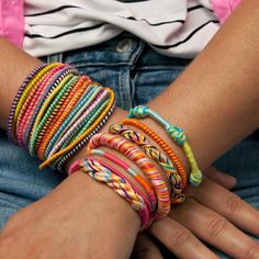 the woman is wearing colorful bracelets on her wrist and holding onto her arm with both hands