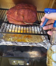 someone is cooking meat on the grill with tongs and water bottles next to it