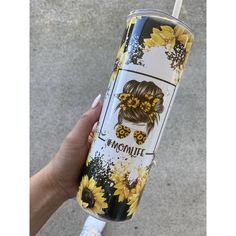 a woman's hand holding up a tumbler with sunflowers on it