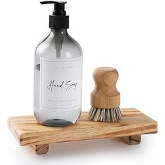 a bottle of hand soap next to a brush on a wooden stand with a white background