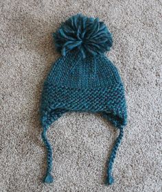 a blue knitted hat laying on top of a carpet next to a cell phone