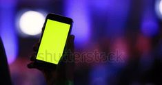 a person holding up a cell phone with a green screen in their hand at night