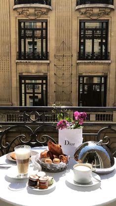 a table with plates and cups on it in front of a building that has windows