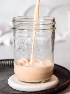 a glass jar filled with milk being poured into it