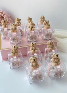 there are many small teddy bears in clear plastic boxes on the table with pink flowers