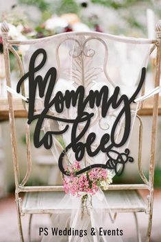 a white chair with flowers on it and the words mommy to bees written in cursive font