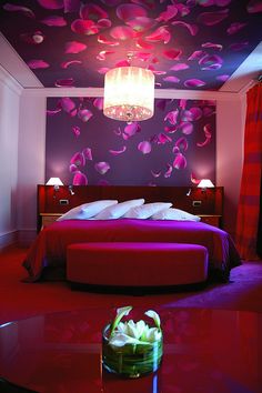 a bedroom with red walls and flooring, two lamps on either side of the bed