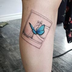 a blue butterfly sitting on top of a woman's leg in front of a mirror