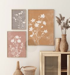 three vases are sitting on a shelf next to two paintings and one is holding flowers