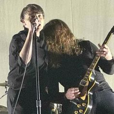 two people on stage with guitars and microphones