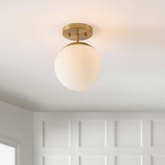 a light that is on the ceiling above a bed in a room with white walls