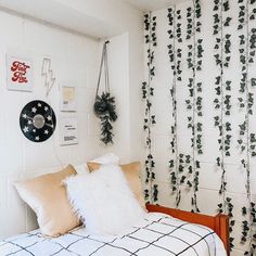 a bedroom with white walls and green plants on the wall behind the headboard, along with a black and white checkered bedspread