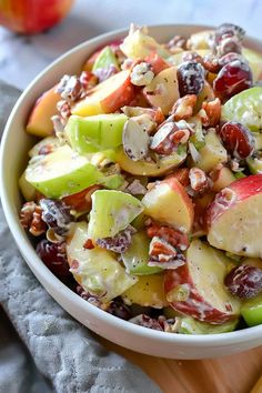 a bowl filled with fruit and nuts on top of a wooden cutting board next to an apple