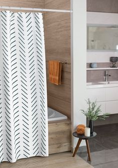 a white shower curtain in a bathroom next to a bathtub and counter with a plant on it