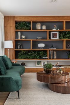 a living room filled with furniture and lots of greenery on the shelves above it