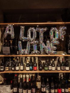 a shelf filled with lots of bottles and balloons that spell out the word alot wine