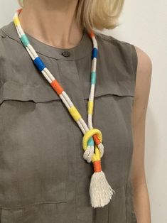 a woman wearing a necklace with multi colored beads and tassels on her neck