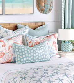 a bed with blue and orange pillows on top of it next to a wall hanging