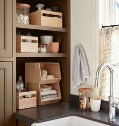 the kitchen sink is next to some shelves with items on them and in front of a window