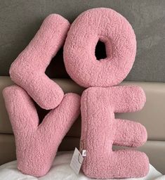 a pink stuffed animal with the word e on it's side sitting on a bed