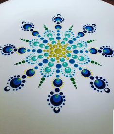 a white plate with blue, yellow and green designs painted on it's surface