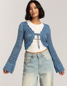 a woman is wearing a blue cardigan with crocheted laces on it