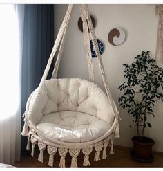 a white hanging chair next to a potted plant