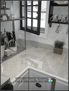 a kitchen with white marble counter tops and gray tile flooring, along with black framed windows