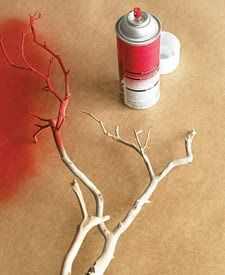 a red spray can sitting next to a white tree with no leaves on the branches