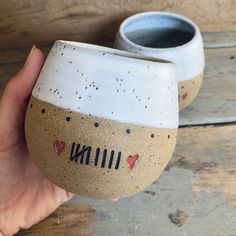 a hand holding a ceramic cup with the word minnesota painted on it