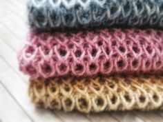 four different colored knitted items are stacked on top of each other in the same pattern