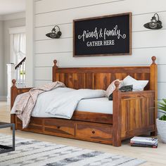 a wooden bed frame with drawers underneath and a sign above it that says, laundry & family gather here