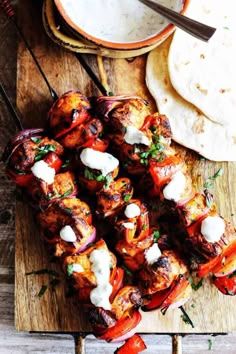 chicken kabobs with tzatzh and yogurt sauce on a cutting board