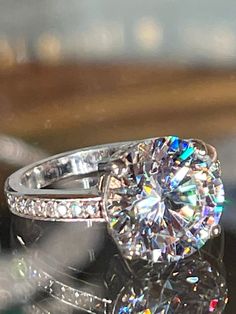 a diamond ring sitting on top of a glass table with its reflection in the background