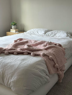 an unmade bed with white sheets and pink blankets on it's headboard