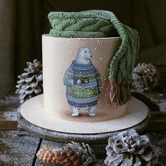 a white and green hat with a bear on it next to pine cones, fir cones and other decorations