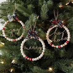 three christmas ornaments hanging from the top of a christmas tree with words on them and bows