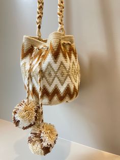 a handbag hanging on a wall with two pom - poms attached to it