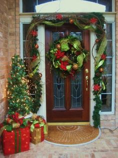 christmas wreaths and presents are on the front porch