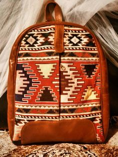 Indulge your wanderlust with our Handmade Bohemian Leather Rucksack, featuring a unique blend of kilim fabric and medium tan/brownish mustard leather. This exclusive design is perfect for all your adventures, whether you're a student, fashion enthusiast, or simply love to explore. Practical and Stylish: Our rucksack is the ideal companion for any journey. Whether you're strolling through city streets, hiking in nature, or commuting to work, this bag effortlessly combines style and functionality. Perfectly Sized: With measurements designed for convenience and comfort, our rucksack is the ideal medium size for all your needs. Its versatile design makes it perfect for a variety of activities and occasions. Expertly Handmade: Each rucksack is handmade with care, ensuring that each one is uniqu Bohemian Handmade Backpack For Travel, Bohemian Handmade Travel Backpack, Bohemian Brown Backpack, Bohemian Style Brown Backpack, Bohemian Brown Standard Backpack, Artisan Brown Backpack For Travel, Bohemian Backpack With Adjustable Strap For Travel, Brown Backpack For Weekend Trips, Handmade Bohemian Standard Backpack