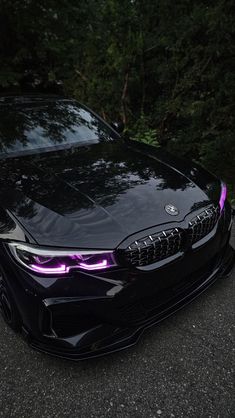 the front end of a black car with purple lights